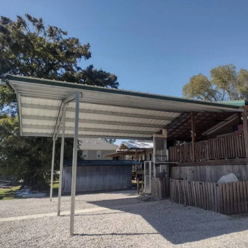 Freestanding metal RV cover and carport built beside a home in South Louisiana.