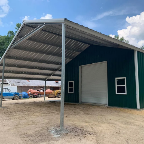 Green metal workshop with a roll-up door, windows and large covered gable extension in Louisiana.